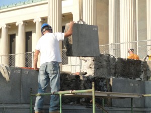 A commercial masonry contractor helping guide a heavy stone in place